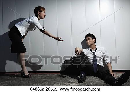 Stock Photography - Woman offering help to man sitting on ground looking sad. Fotosearch