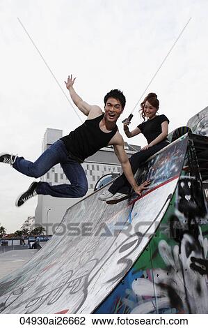 Stock Image - Young couple hanging out at skate park together. Fotosearch