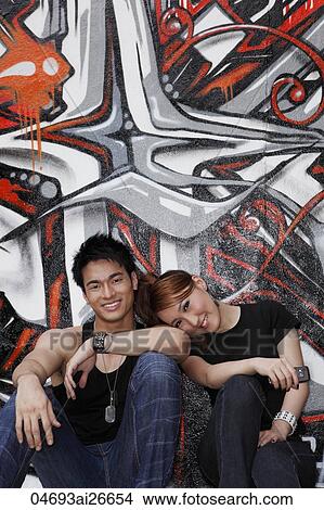 Young couple sitting down next to graffiti wall View Large Photo Image Picture - Young couple sitting down next to graffiti wall. Fotosearch