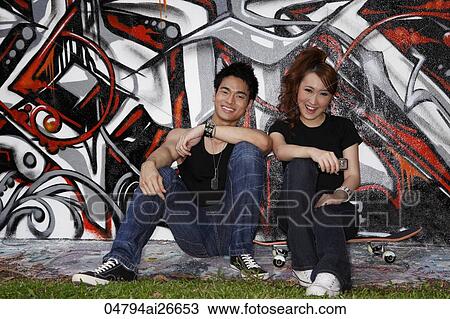 Young couple sitting down next to graffiti wall View Large Photo Image Stock Image - Young couple sitting down next to graffiti wall. Fotosearch
