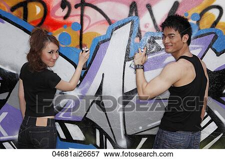 Stock Photo - young couple spay painting graffiti on a wall together. Fotosearch