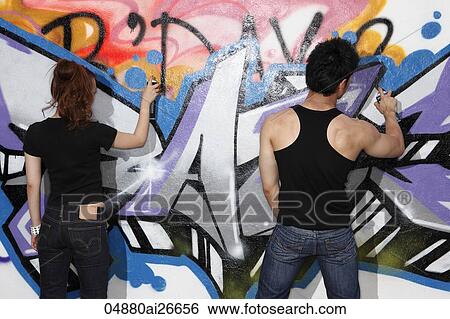 Young couple spray painting graffiti on a wall View Large Photo Image Stock Photograph - Young couple spray painting graffiti on a wall. Fotosearch