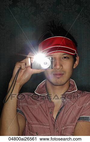 Young man holding a camera to his eye with flash on View Large Photo Image Stock Image - Young man holding a camera to his eye with flash on. Fotosearch