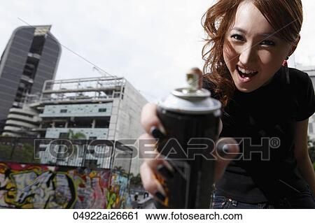Young woman holding spray paint can towards camera View Large Photo Image Stock Image - Young woman holding spray paint can towards camera. Fotosearch