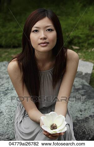 Young woman holding white flower and looking at camera View Large Photo Image Stock Image - Young woman holding white flower and looking at camera. Fotosearch