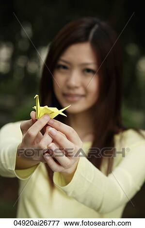 Young woman holding yellow crane View Large Photo Image Stock Photo - Young woman holding yellow crane. Fotosearch