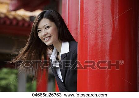 Young woman looking out from red pillars smiling View Large Photo Image Stock Image - Young woman looking out from red pillars smiling. Fotosearch
