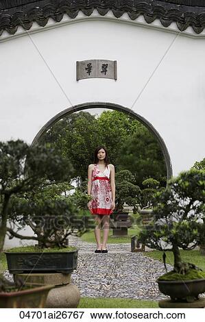 Stock Photo - Young woman standing in Chinese garden. Fotosearch
