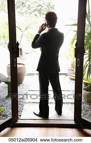 back shot of a man wearing a suit and talking on the phone on patio View Large Photo Image Picture - back shot of a man wearing a suit and talking on the phone on patio. Fotosearch