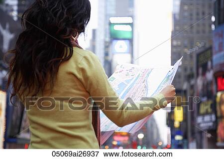 Stock Photo - back view of woman holding map in city. Fotosearch