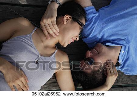 Stock Image - couple laying on backs and looking at each other. Fotosearch
