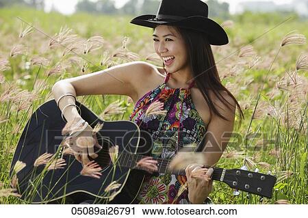 Happy woman playing guitar in grassy field View Large Photo Image Stock Image - Happy woman playing guitar in grassy field. Fotosearch
