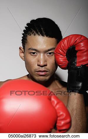 Stock Image - head shot of young man with red boxing gloves. Fotosearch