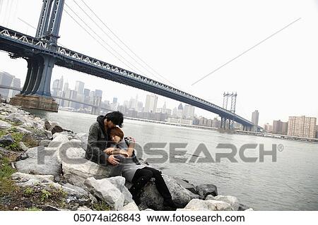 man and woman holding each other on rocks in front of bridge View Large Photo Image Stock Image - man and woman holding each other on rocks in front of bridge. Fotosearch