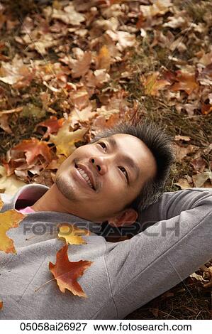 Stock Photo - man laying down on fallen leaves. Fotosearch