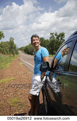 man leaning against car next to road View Large Photo Image Stock Image - man leaning against car next to road. Fotosearch