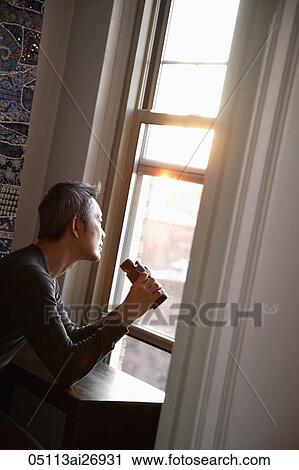 Stock Image - man looking out window with binoculars. Fotosearch