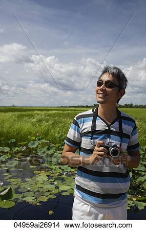 Picture - man outside holding camera looking up. Fotosearch