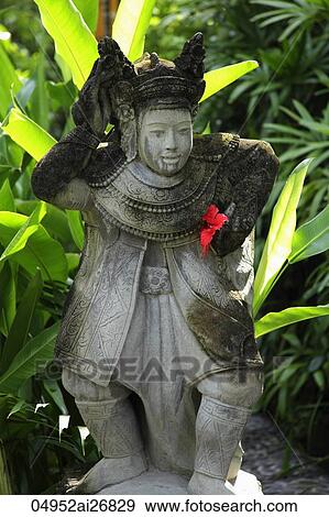 Stock Photo - stone Hindu statue with red flower. Fotosearch
