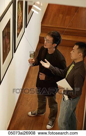 Stock Photo - Two men looking at artwork. Fotosearch