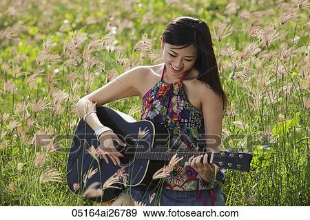Woman playing guitar outside in grassy field. View Large Photo Image Stock Photo - Woman playing guitar outside in grassy field.. Fotosearch