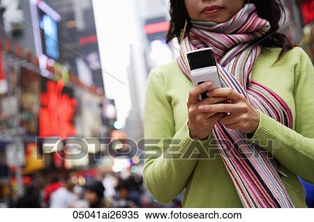 Stock Photography - woman wearing scarf holding phone on street. Fotosearch