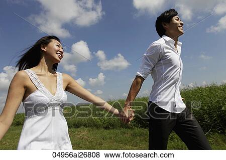Stock Photo - young couple holding hands and smiling outside. Fotosearch