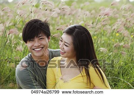 Stock Photo - young couple sitting in field together laughing. Fotosearch
