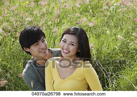 Young couple sitting on grass smiling together View Large Photo Image Stock Photo - Young couple sitting on grass smiling together. Fotosearch