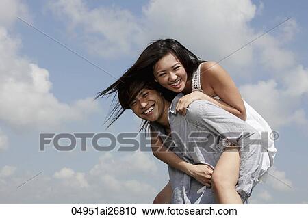 young man carrying a woman on his back laughing, blue sky with clouds as background View Large Photo Image Stock Image - young man carrying a woman on his back laughing, blue sky with clouds as background. Fotosearch
