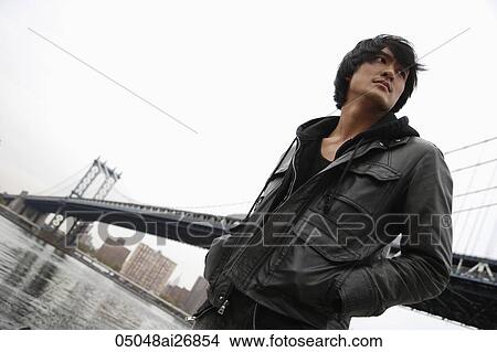 young man wearing a coat in front of bridge View Large Photo Image Picture - young man wearing a coat in front of bridge. Fotosearch