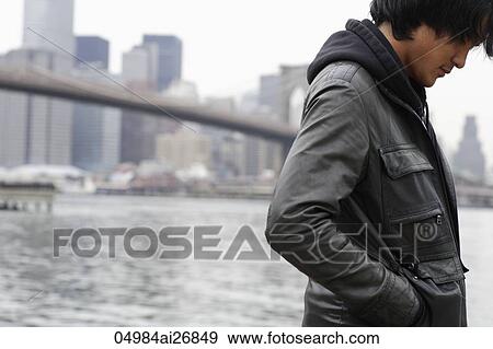 young man wearing a coat looking down, city skyline as background. View Large Photo Image Stock Photo - young man wearing a coat looking down, city skyline as background.. Fotosearch