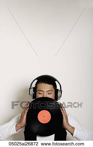 young man with earphones covering half of his face with a record View Large Photo Image Stock Image - young man with earphones covering half of his face with a record. Fotosearch