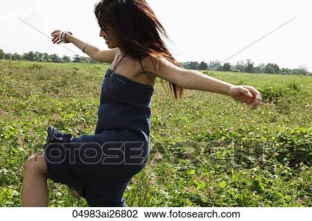 young woman dancing in grassy field View Large Photo Image Stock Image - young woman dancing in grassy field. Fotosearch
