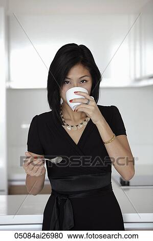 Stock Image - young woman drinking out of coffee mug. Fotosearch