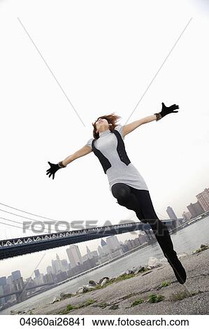 young woman jumping in air with arms outstretched View Large Photo Image Stock Image - young woman jumping in air with arms outstretched. Fotosearch