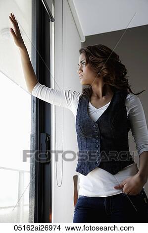 Picture - young woman looking out window. Fotosearch