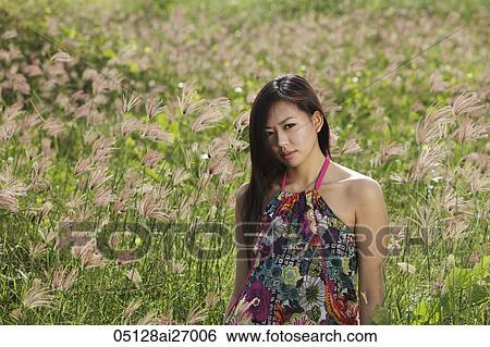 Stock Photograph - young woman standing in field of grass. Fotosearch
