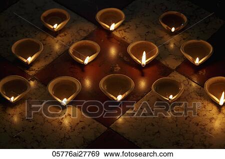 Stock Photo - A group of lit clay oil lamps on floor. Fotosearch