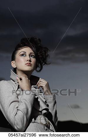 Asian woman wearing coat outside with dark clouds in background View Large Photo Image Stock Photograph - Asian woman wearing coat outside with dark clouds in background. Fotosearch
