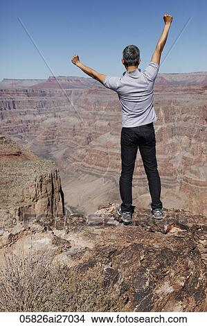 Picture - back view of man standing with arms outstretched. Fotosearch