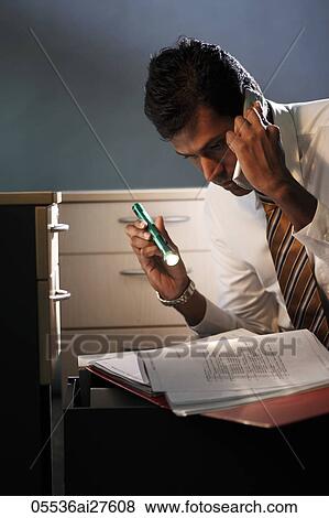 Stock Photo - Business man looking at documents with flashlight at night. Fotosearch