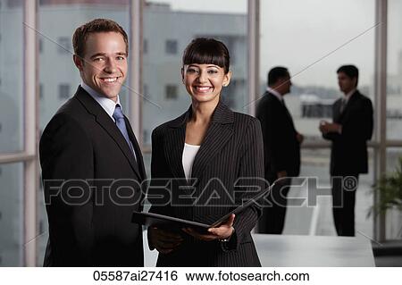 Caucasian and Indian woman smiling at camera with two colleagues in background. View Large Photo Image Stock Photograph - Caucasian and Indian woman smiling at camera with two colleagues in background.. Fotosearch