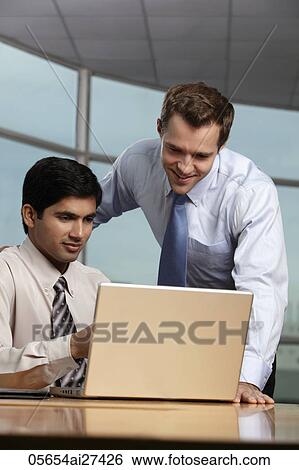 Caucasian man looking at laptop with Indian man View Large Photo Image Stock Photograph - Caucasian man looking at laptop with Indian man. Fotosearch