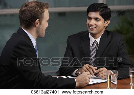 Caucasian man talking to Indian man at table View Large Photo Image Stock Image - Caucasian man talking to Indian man at table. Fotosearch