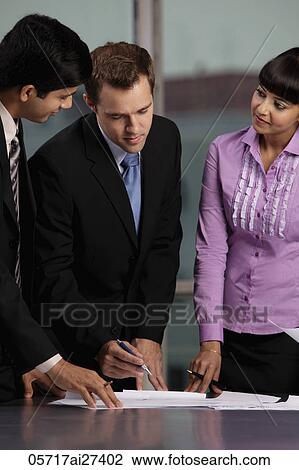 Stock Image - Caucasian man talking to two Indian collegues. Fotosearch