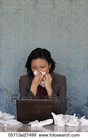Chinese woman sitting at lap top blowing her nose in a tissue View Large Photo Image Stock Photo - Chinese woman sitting at lap top blowing her nose in a tissue. Fotosearch