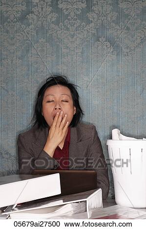 Chinese woman sitting at messy desk yawning View Large Photo Image Stock Image - Chinese woman sitting at messy desk yawning. Fotosearch