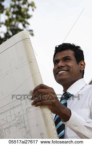 Close up of business man holding plans and smiling View Large Photo Image Stock Photo - Close up of business man holding plans and smiling. Fotosearch