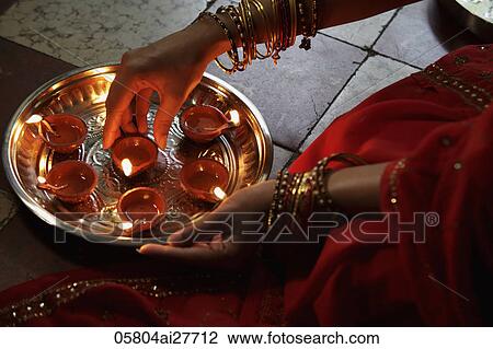 Close up of woman wearing a sari, putting oil lamps on silver tray View Large Photo Image Stock Image - Close up of woman wearing a sari, putting oil lamps on silver tray. Fotosearch